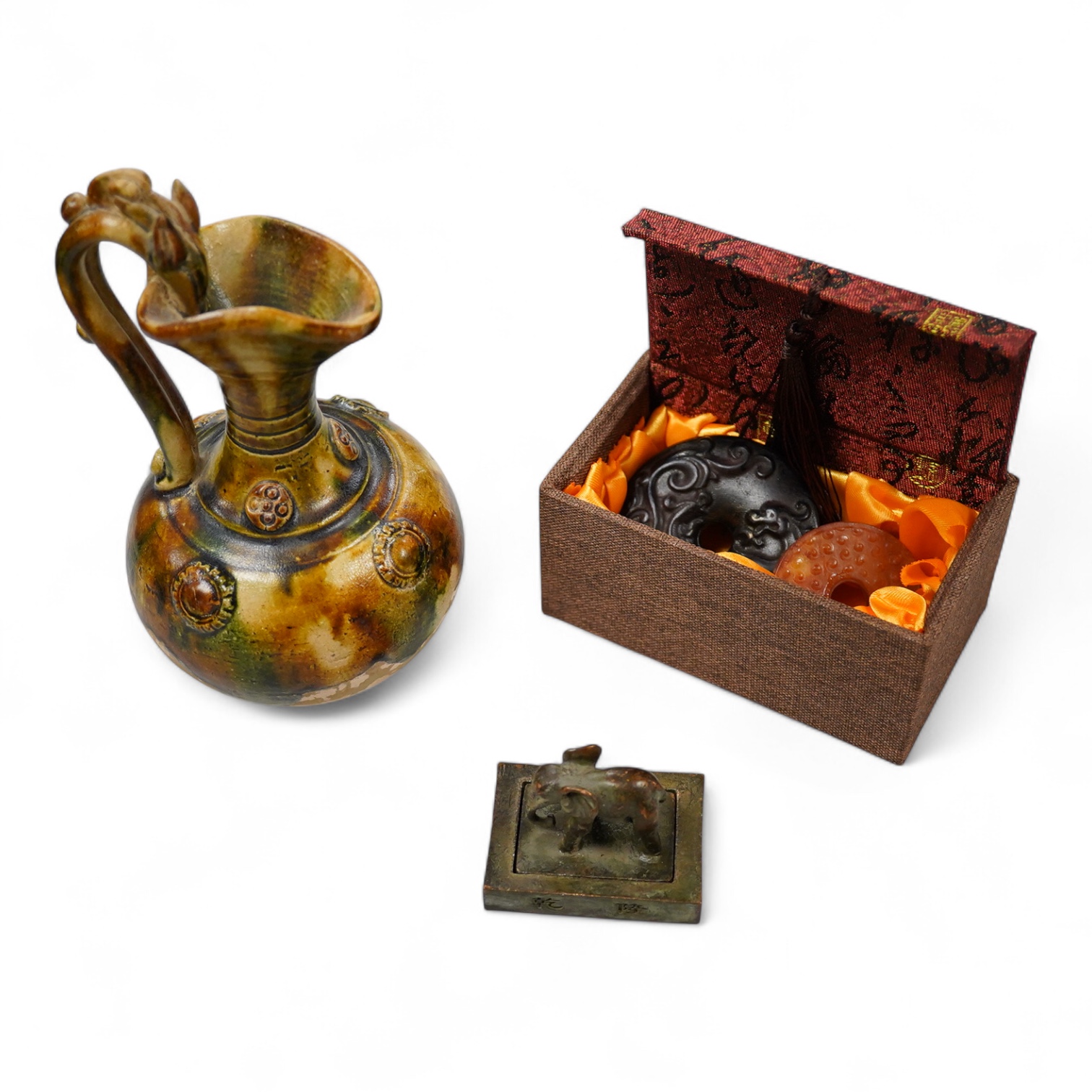 A Chinese pottery jug, two hardstone discs and a metal seal. Jug 17.5cm high